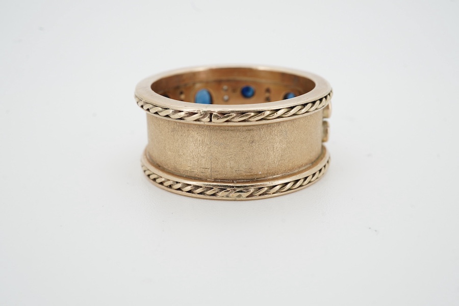 A sapphire and diamond ring, the wide band set to the front with oval and circular-cut sapphires spaced by lines of single-cut diamonds, between rope-twist borders, size V1/2, no assay marks, gross weight 12 grams, Condi